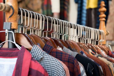 Bir mağazadaki raftan farklı renklerde kıyafetler sarkıyor.