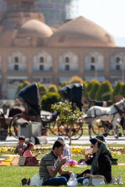 2 Mart 2019: İranlılar dinleniyor ve Naghsh-e Cihan Meydanı 'ndaki çimlerde piknik yapıyorlar. İsfahan, İran