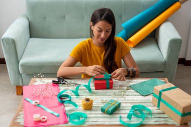 El yapımı el yapımı hediyeleri evdeki masaya saran kadın.