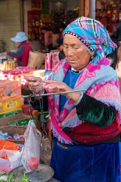 March 14, 2019: An ethnic elder woman selling some vegetables at the market, Xizhou, Yunnan, China — Stock Photo, Image