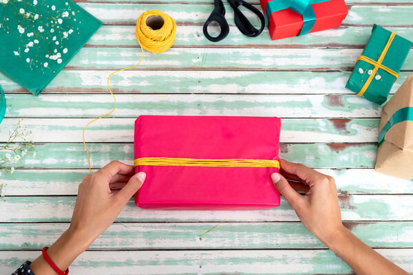 Woman wrapping handmade craft gifts on the table at home
