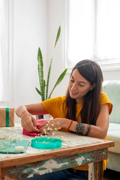 집 식탁 위에서 수제 공예품을 싸고 있는 여성 — 스톡 사진
