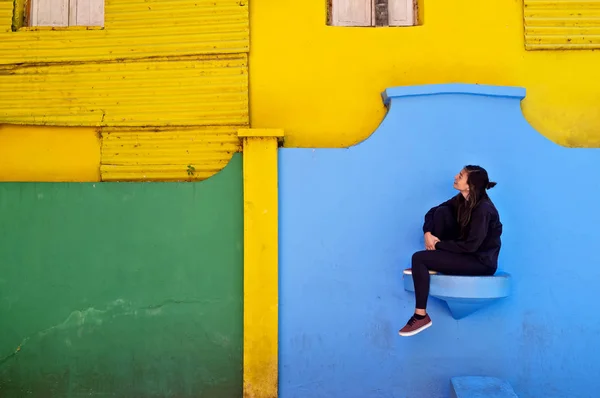 カミニート通りのカラフルな壁の前に座っている観光客の女性、ブエノスアイレス — ストック写真