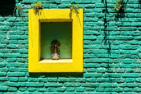 Zelená a žlutá cihlová zeď se sochou na ploše Caminito v La boca, Buenos Aires, Argentina — Stock fotografie