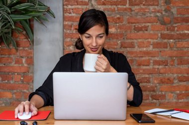 Evde dizüstü bilgisayar ve belgelerle çalışan genç bir kadın.