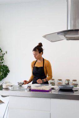 Esmer kadın modern bir mutfakta yumurta kırıyor.