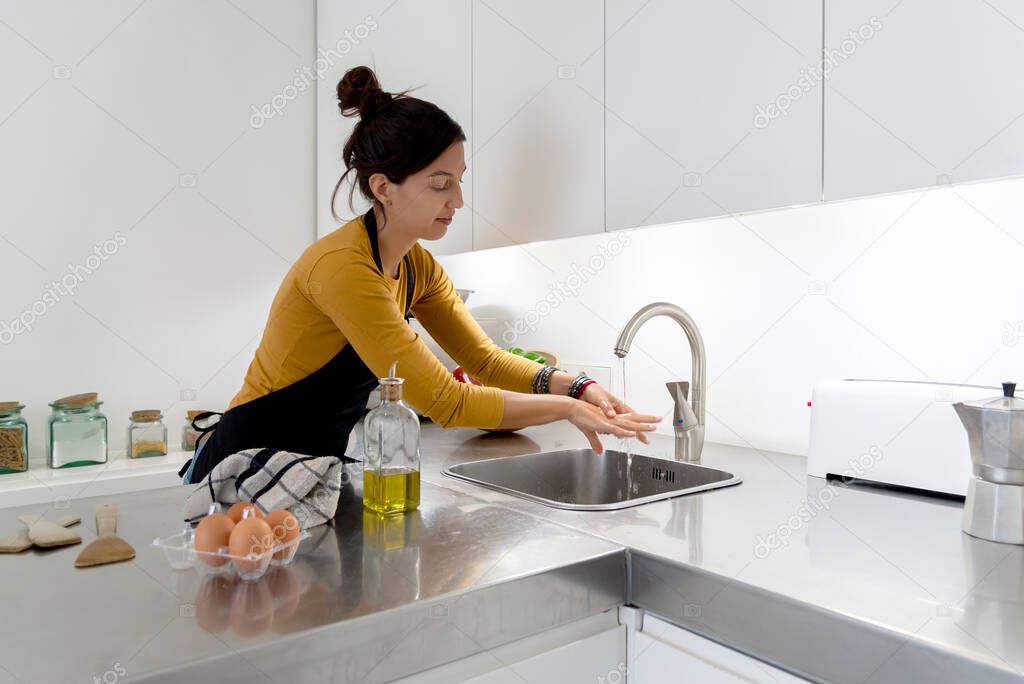Brunette woman washing her hands after cooking on the kitchen