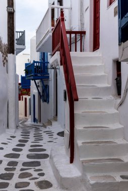 Yunanistan 'ın Mykonos kentindeki güneşli sokakta merdivenleri ve kapıları olan beyaz bir ev..