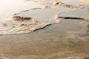 Türkiye 'nin Pamukkale kentindeki beyaz kireçtaşı dağlarındaki sakin gölet güneşli bir günde 