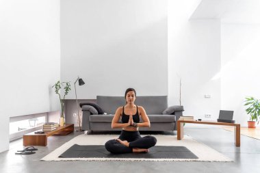 Yoga yapan çekici kadın rahat evinde meditasyona poz veriyor.