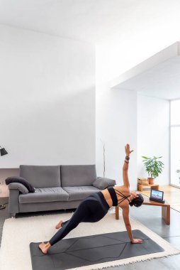 Fit Kadın tabletindeki online eğitim programını kullanarak minderinde yoga yapıyor.