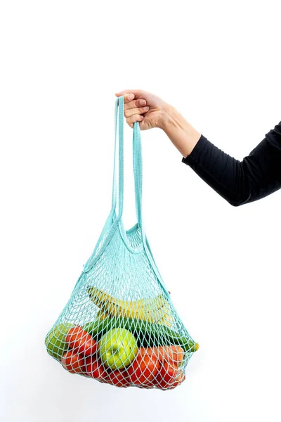 Girl holding reusable string bag full of organic vegetables