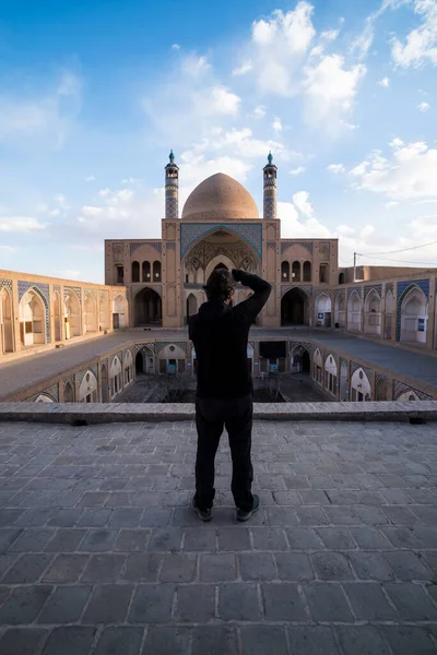 Back view of photographer man taking shots of mosque in Khasan, Iran.