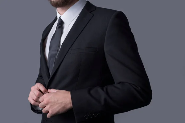 Gri arka planda duran takım elbiseli bir erkek işadamının portresi. Metin için boş alanı olan basit iş konsepti.