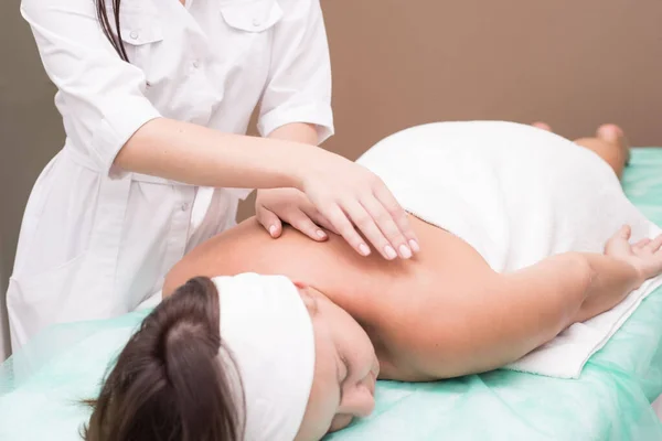 Manos de una masajista, de cerca haciendo masaje de espalda a una joven, en un salón de spa — Foto de Stock