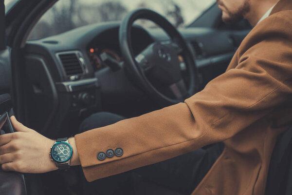 Портрет молодого парня в деловой одежде, бизнесмена тридцати лет открывает дверь машины к выходу. В интересной авторской работе
