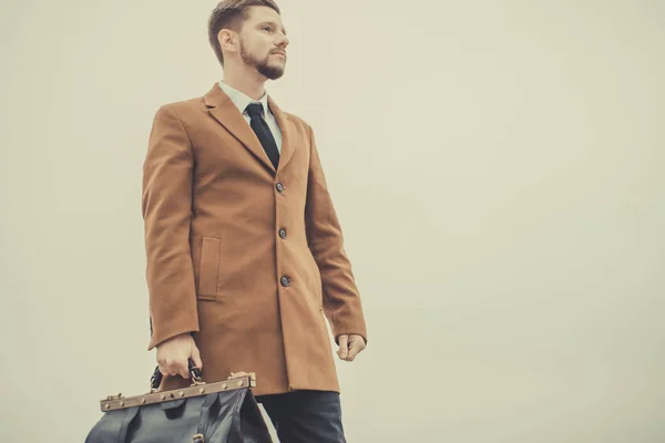 Portret van een dertigjarige man met een baard, in een zakelijke stijl, met een leren tas in zijn handen. Tegen de hemel, straatstijl. Bedrijfsconcept. In creatief kleuren. — Stockfoto