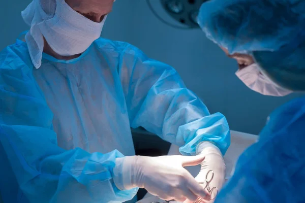 Çocuk cerrahları ürolojik ameliyat yaparlar. Maskeli bir adam ve bir kadın ve mavi steril bir elbise, ameliyathanede.. — Stok fotoğraf