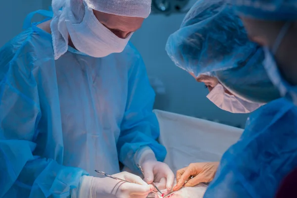 Çocuk cerrahları ürolojik ameliyat yaparlar. Maskeli bir adam ve bir kadın ve mavi steril bir elbise, ameliyathanede.. — Stok fotoğraf