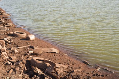 Atık tarafından kirletilmiş, nehir kıyısındaki makine lastikleri.