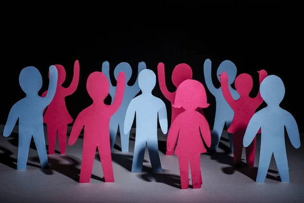 concept of people strike and protest. Paper multi-colored little men with raised hands, on a dark background. Freedom and independence.