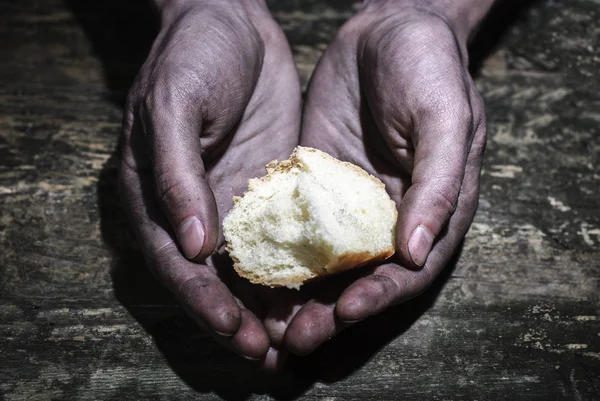 Manos sucias de un hombre sosteniendo una corteza de pan. Suplicando por una mano de esperanza. Da esperanza. El concepto de limosna y caridad — Foto de Stock