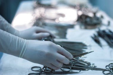 Cerrahın eli, steril eldivenlerle, teşhis manipülasyonları yapmadan önce aleti tutuyor. Ameliyathanedeki hemşirenin elleri.