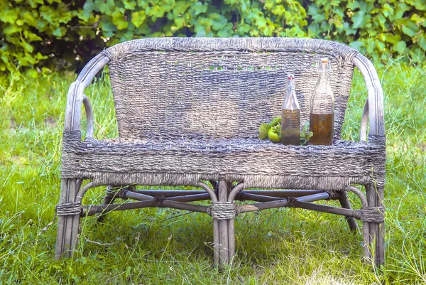 Vinagre de maçã, suco, limonada, cidra, derramado em garrafas velhas. Em pé num banco de vime. Estilo de país — Fotografia de Stock