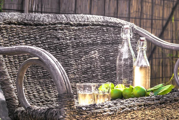 Sidro di mele, in bottiglie d'epoca, poggia su una panchina di vimini. In stile rustico . — Foto Stock