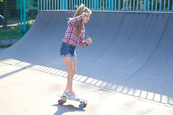 Μικρό κορίτσι ιππασία ένα skateboard στο γήπεδο του αθλητισμού — Φωτογραφία Αρχείου