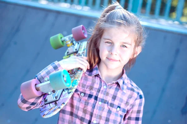 Retrato de uma linda menina segurando um skate em seu ombro — Fotografia de Stock