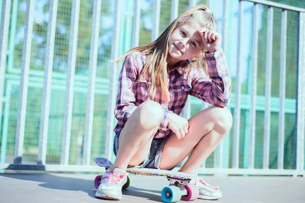 Portret van een mooi klein meisje zittend op een skateboard — Stockfoto