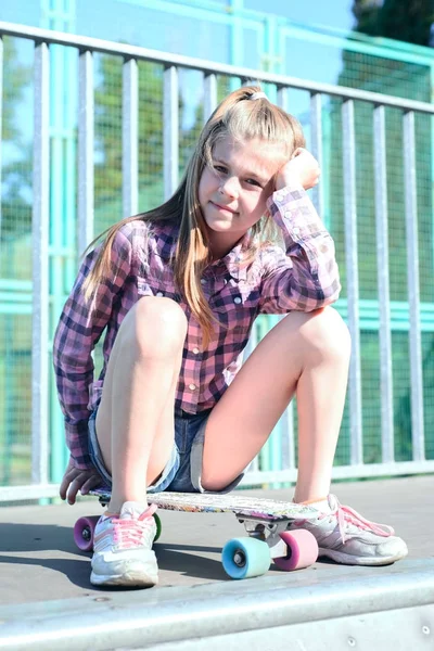 Retrato de uma menina sentada em um skate — Fotografia de Stock