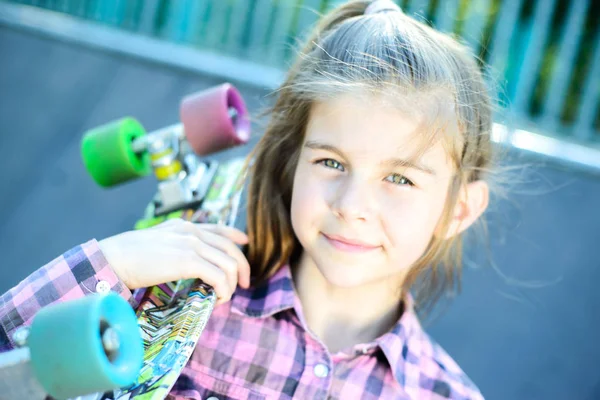 Retrato de uma linda menina segurando um skate em seu ombro — Fotografia de Stock