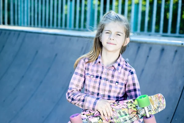 Bonito menina segurando um skate multicolorido — Fotografia de Stock