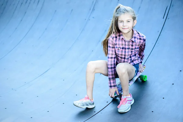 Menina sentada em um skate, skatepark na rua — Fotografia de Stock