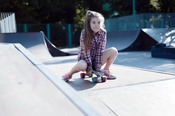 스케이트보드 위에 앉아 있는 아름다운 십 대 소녀의 사진 — 스톡 사진