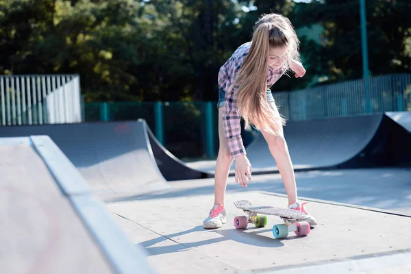 Tonårstjej utför ett trick med en skateboard på idrottsplanen — Stockfoto