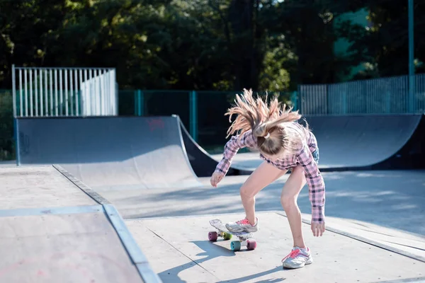 Tonårstjej utför ett trick med en skateboard på idrottsplanen — Stockfoto