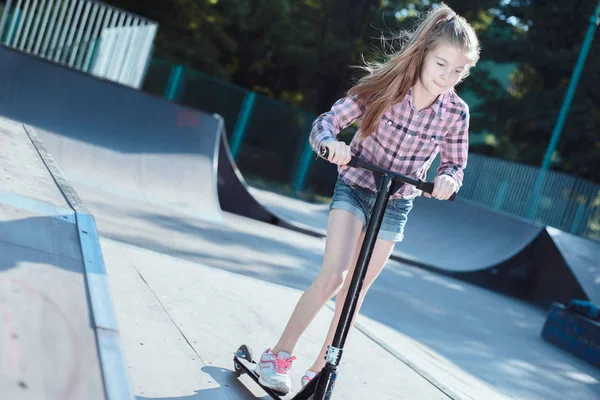 Estilo de vida saudável na infância. Retrato de uma menina pequena e ativa montando uma scooter de atividades esportivas infantis . — Fotografia de Stock