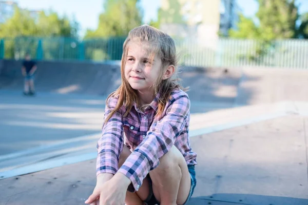 Portrait of a beautiful little teenage girl, seated smiling outdoors — Stock Photo, Image