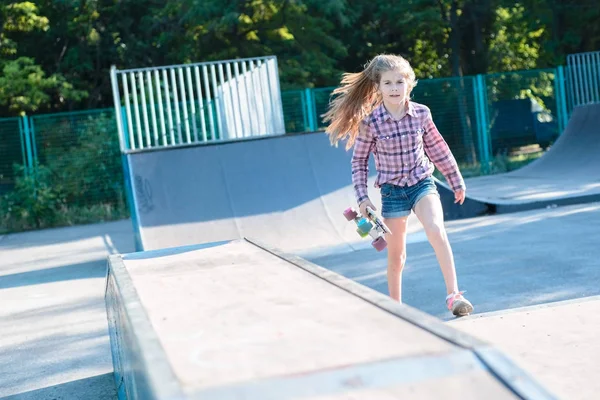 Bambina sullo skatepark, sta arrivando tenendo lo skateboard — Foto Stock