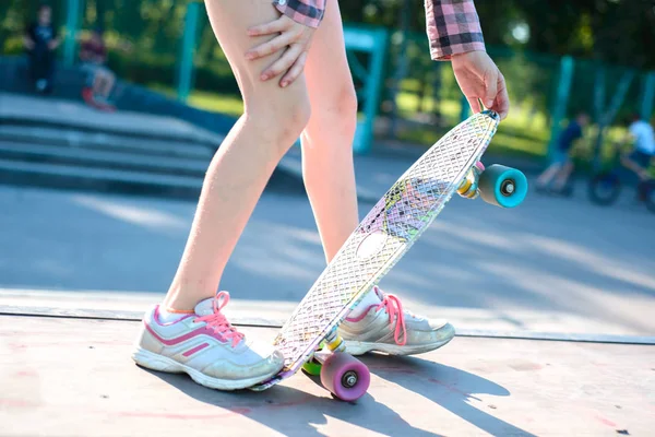 Porträt eines kleinen Mädchens im Teenageralter, das in der Hand ein Skateboard hält und trainiert, um den Trick auszuführen — Stockfoto