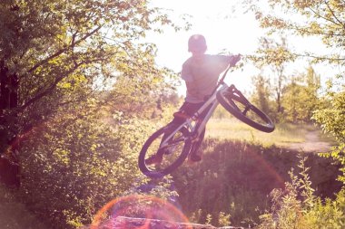 Genç sporcu, antrenman yapıyor ve ormanda güneşin batışına karşı bisiklet dublörlüğü yapıyor. etkin yaşam biçimi