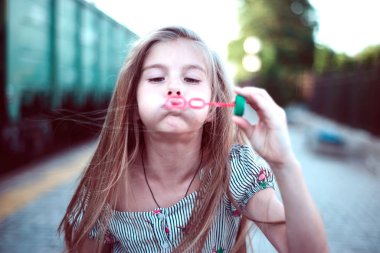 Kız istasyonda baloncuk çıkarıyor.