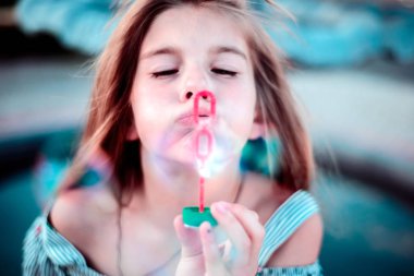 Sabun köpüğü üfleyen küçük güzel bir kızın portresi.