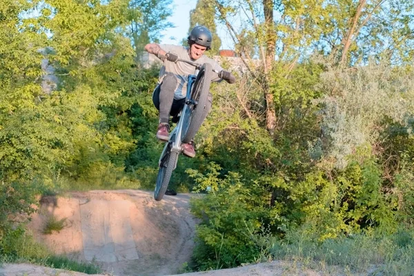 Jonge man fietser doet sprongen en trucs op een fiets. in het bos tegen de ondergaande zon — Stockfoto