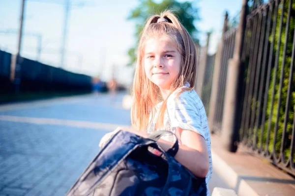 Menina feliz com mochila sorrindo esperando por trem na estação — Fotografia de Stock