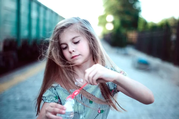 Menina bonita com luxuoso cabelo sopra bolhas — Fotografia de Stock