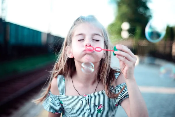 Retrato de uma linda menina soprando bolhas na ferrovia — Fotografia de Stock